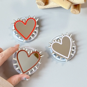 Three heart-shaped mirror phone grips in red, white and brown with sunburst edges