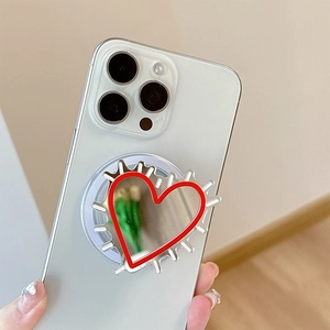Red heart-shaped mirror phone grip and expanding stand attached to a white smartphone