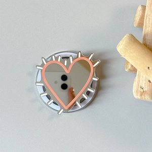 Detail view of heart mirror phone grip with pink cartoon splatter edges and pop socket base