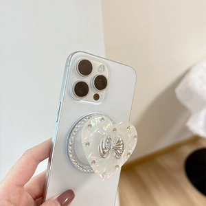Pearly heart phone grip with rhinestone border and silver bow on white smartphone