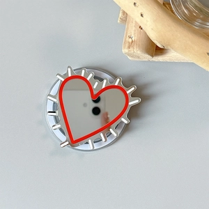 Detail of heart-shaped mirror phone grip with red line accents and white jagged edges
