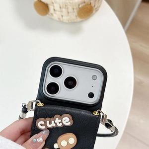 Close-up of black leather iPhone case featuring cute 3D charms and crossbody lanyard