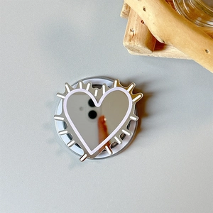 Detailed view of heart-shaped mirror phone grip with white artistic line patterns