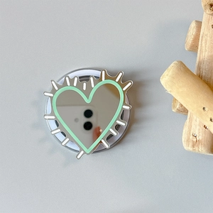 Detail of silver heart-shaped mirror phone grip with mint green border and radial design