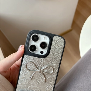 Detail of silver pleated leather phone case with metallic bow for iPhone 16 Pro Max