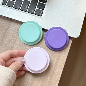 Close-up of matte pastel phone grip stands in mint and purple colors on a wooden desk
