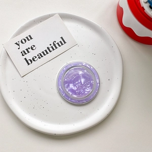 Close-up of a purple seashell textured MagSafe phone grip on a white ceramic plate