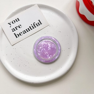 Macro shot of purple marble shell pattern magnetic Magsafe phone grip on a white ceramic plate
