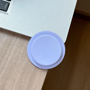Detail shot of a lavender matte round magnetic phone grip on a silver laptop surface