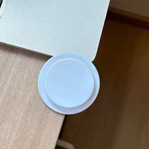 Close-up of a minimalist white matte magnetic phone grip on a wooden desk setup