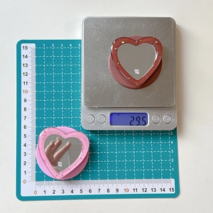 Detailed view showing heart-shaped mirror phone grip weights 29.5g and measures 50mm