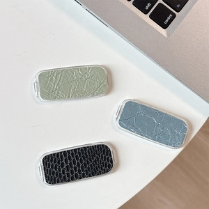 Three acrylic phone grips with snakeskin and crinkle textures on a white desktop