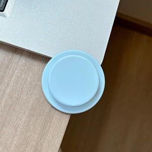 Macro detail of foldable light blue and white magnetic phone socket on a wooden desk