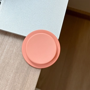 Detail shot of a matte pink magnetic phone socket holder on a wooden desk setup
