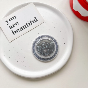 Macro shot of circular MagSafe phone grip with grey marble texture on a white plate
