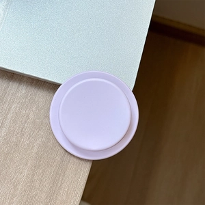 Detail view of a matte light purple magnetic circular phone grip on a modern desktop