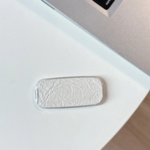 Macro view of a minimalist silver snakeskin texture phone mirror stand on a white desk