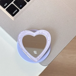 Detail of purple glitter heart phone grip with mirror and mine. text on laptop