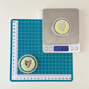 Detail view of heart-shaped glitter phone grip with rhinestones showing weight and size