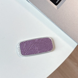 Detailed texture of purple cream eyeshadow with metallic luster in clear rectangular case