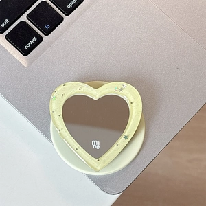 Detail of glitter heart phone grip with mirror on a silver laptop surface