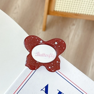 Reddish brown butterfly phone grip with glitter and star sequins on a white background