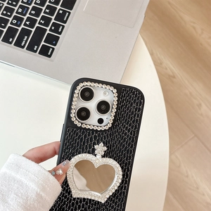 Macro shot of phone case with black faux-leather texture, heart mirror and rhinestones