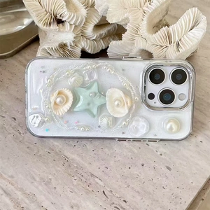 Close-up of 3D pearl and shell decorations on a glittery cream iPhone phone case