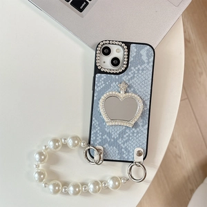 Detail of blue snake texture phone case with heart mirror crown and pearl strap