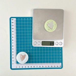 Dettaglio del supporto cellulare a cuore glitterato con incisione su tappeto blu