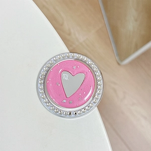 Detailed close-up of a heart-shaped phone grip with rhinestones and pink glitter finish