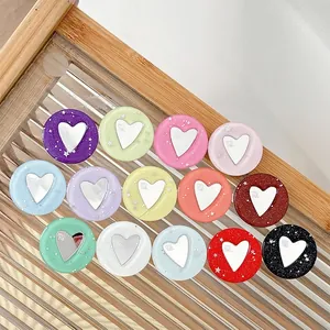 Set di 14 supporti per telefono a cuore glitterato colorato su un vassoio di vetro