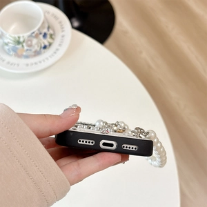 Detailed close-up of rhinestone bow phone case with pearl wrist strap and precision cutouts