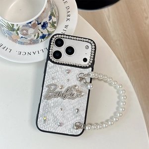 Detail of white leather iPhone case with rhinestone lens ring, Barbie logo and pearl strap