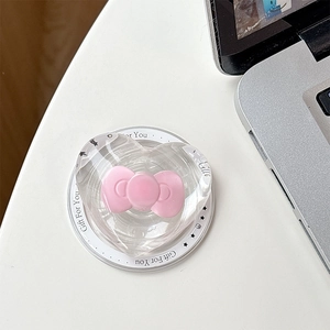 Close-up of heart-shaped MagSafe phone grip with pink bow and Gift For You text on desk