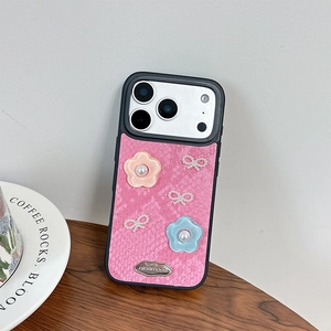 Detailed shot of pink snakeskin phone case with 3D flowers and pearl bows on wood surface