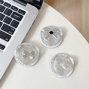 Transparent heart-shaped MagSafe phone grips with bow and floral accents on white surface
