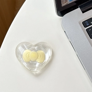 Detailed close-up of a transparent heart-shaped Magsafe phone grip with yellow bow decoration