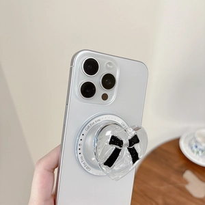 Detailed view of a transparent heart-shaped phone grip with a black bow and MagSafe base