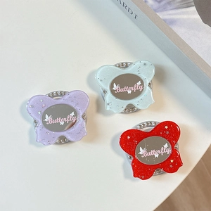 Close-up of glittery butterfly phone grips with oval mirrors and rhinestone edges