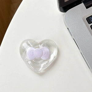 Macro shot of heart-shaped magnetic phone grip with light purple resin bow on white desk