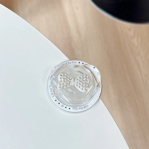 Close-up of heart-shaped transparent phone grip with a sparkling diamond bow accent