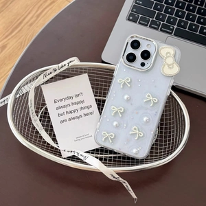 Close-up of iPhone case featuring 3D bow, pearls, and glitter on a pale blue finish