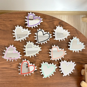 Colorful heart-shaped mirror phone grips set with wavy edges on a wooden background