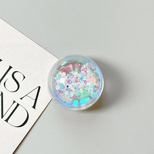 Detail of round transparent phone grip with iridescent purple and blue glitter filling