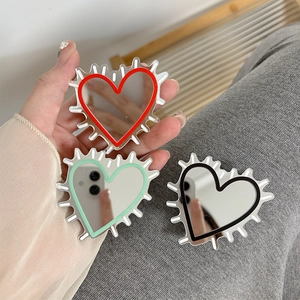 Close-up of heart-shaped mirror phone grips in red, mint green, and black colors