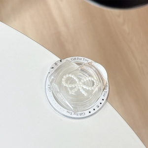 Detail of transparent heart phone grip with pearl bow on a decorative gift card