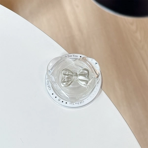 Detail shot of heart-shaped transparent MagSafe phone grip with silver bow accent