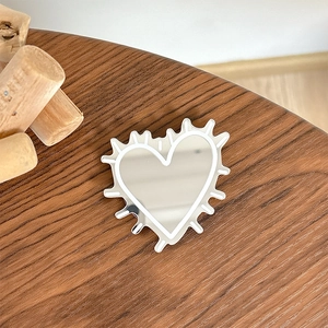 Macro shot of silver heart mirror phone grip on dark wooden table background