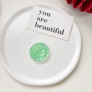 Close-up of mint green shell texture collapsible phone grip on white ceramic plate